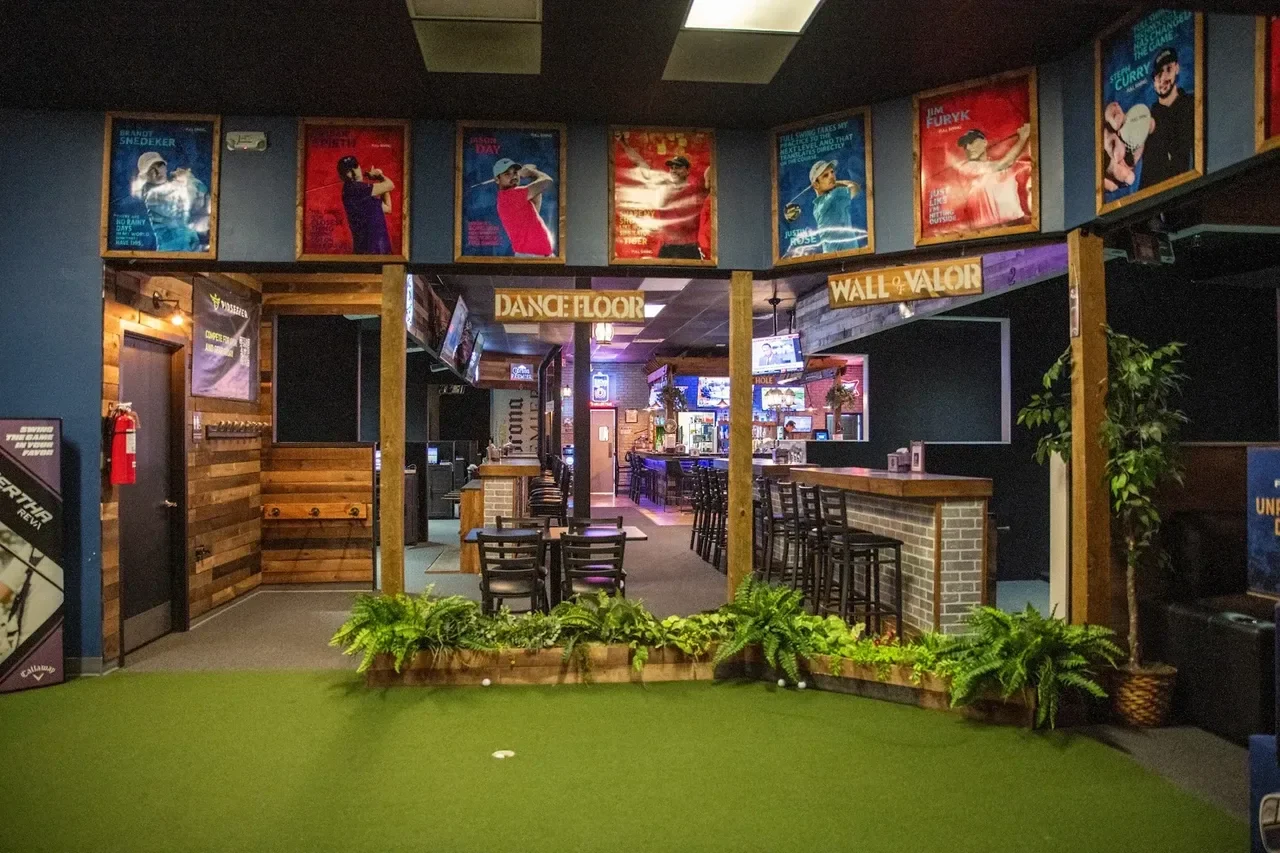 A wide view of Stix Germantown with turf, plants, simulator seating, and the bar